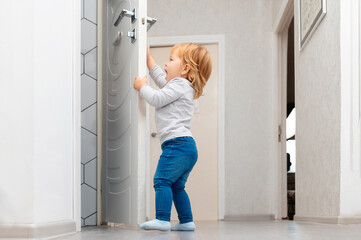 Fototapeta na wymiar A little toddler opening the door. Protecting children from accidents. Low angle view