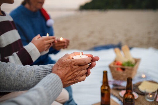 Close up of unrecognizable people celebrate Christmas and holding candles on beach.