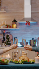 Couple raising glasses of champagne celebrating christmas eve. Festive man and woman sitting at table eating chicken and drinking alcohol for traditional dinner on seasonal holiday.