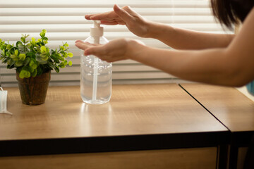 A woman are pump alcohol gel bottle at window to clean and wash hand and protect from virus and COVID19