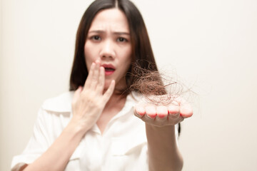 Asian women looking hair loss falling in hand with a worry