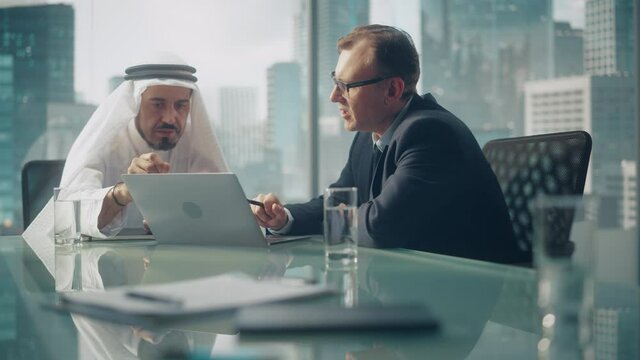 International Business Consultant Advices on Diversification of Investment Portfolio to Successful Arab Company Owner. Multicultural Meeting in Modern Office Between American and Emirati Businessman.