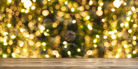 Wooden table top with a beautiful bokeh on a Christmas tree with a warm shade of yellow and green....