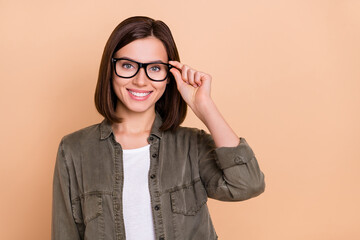 Photo of positive lady hold specs look camera eye examination concept wear khaki shirt isolated beige color background