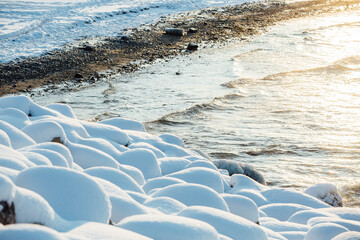 Winter color sunset at sea. A bright color sunset by the sea on a winter day. The beach is snowy. People walk along the sea. The beach is snowy.