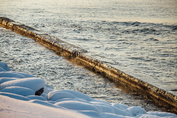 Winter color sunset at sea. A bright color sunset by the sea on a winter day. The beach is snowy. People walk along the sea. The beach is snowy.
