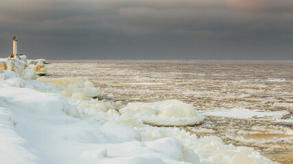 Winter color sunset at sea. A bright color sunset by the sea on a winter day. The beach is snowy. People walk along the sea. The beach is snowy.