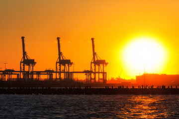 Fototapeta na wymiar Me Port 3 cranes silhouette sun