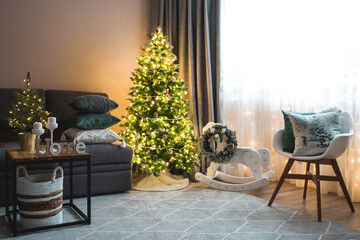 Cozy decor in gray-green tones in the interior of the Christmas room, a Christmas tree decorated with garlands, gifts, a wooden horse. A festive living room in the house. New Year's holidays 2022