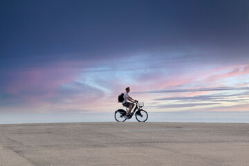 Isolated man riding a bicycle against a sunset sky. Negative space.