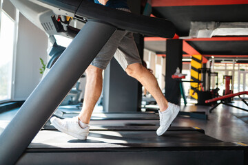 A sporty man runs on a treadmill in the gym. Legs close-up. The concept of cardio training