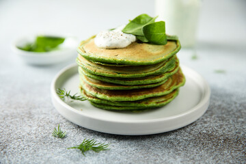 Traditional homemade spinach pancakes with sour cream - obrazy, fototapety, plakaty