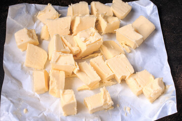 Fresh, organic Butter on white paper, dairy farm product. Dark background, top view.