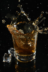 glass of whiskey into which ice falls. frozen splashing drops