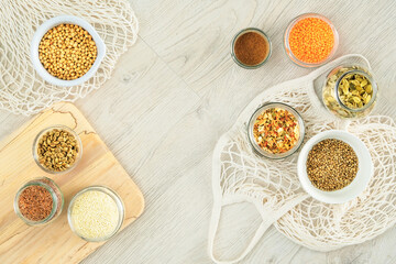 Zero waste shopping and sustanable lifestyle concept. Various farm organic products in glass jars on a light wooden background. Copy space, top view.