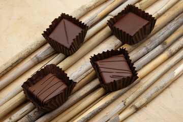 Chocolate candies in paper cups on a dry reed background. Four pralines in brown paper cups. Craft chocolate in Ukraine.