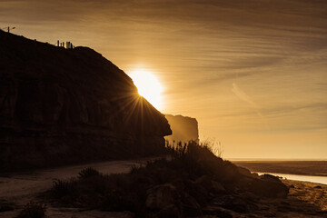 Silhouettes of cliffs cut out by the sunset light on the beach at Foz do Sizandro, São Pedro da Cadeira PORTUGAL
