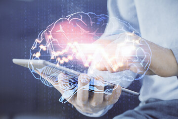 Double exposure of man's hand holding and using a digital device and brain hologram drawing. Data...