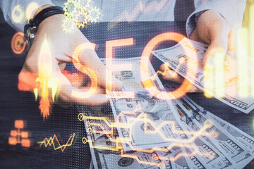 Multi exposure of seo drawing hologram and us dollars bills and man hands.