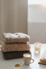 Fototapeta na wymiar cozy home atmosphere and still life with coffee, candle and sweaters