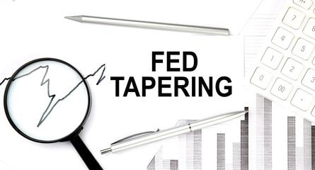 FED TAPERING text on document with pen,graph and magnifier,calculator