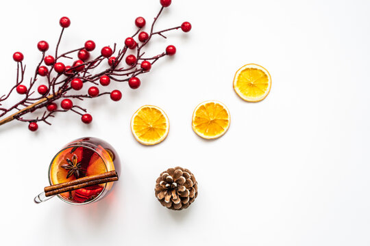 Ein Glas Gl&uuml;hwein mit Gew&uuml;rzen und getrocknete Orangenscheiben auf einem wei&szlig;en Hintergrund. Weihnachten, Flat lay.