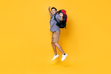 Fototapeta na wymiar Portrait of excited young Caucasian male tourist backpacker jumping in mid-air isolated on yellow studio background for travel and vacation concept