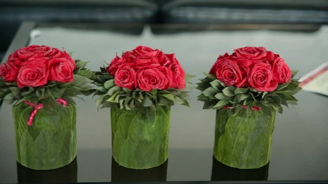 Table setting with flowers of red roses. three small bouquets of roses in boxes Festive table decor. modern white interior. fake roses. Bouquet of artificial flowers
