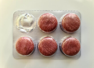 Packs of red pills packed in blisters with copy space isolated on a background. Focus on...