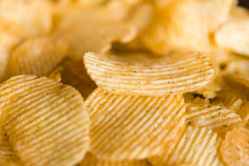 Crispy potato chips in a plate on metallic black grunge background	