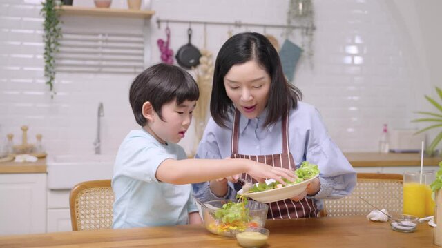 A happy asian family in the kitchen. Mother and son are making healthy food. care, connection and activities in the house