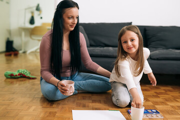 mother and her daughter painting with water colors at home