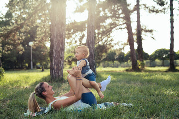 mother and her baby boy outdoor in park doing physical exercises