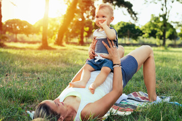 mother and her baby boy outdoor in park doing physical exercises