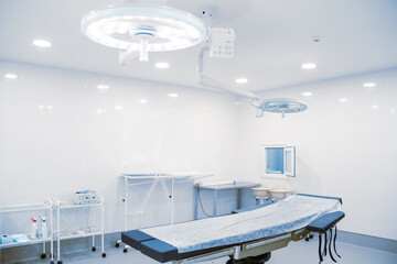 Empty operating room in a hospital. Surgical equipment with operating table. Medical device for emergency patient in blue tone style. Blank Emergency Surgery Room. Clinic interior for background.