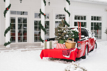 Red pickup truck with Christmas New Year decor in the courtyard of a suburban snow house