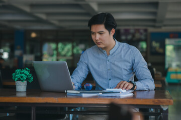 Obraz premium Professional young Asian businessman using computer laptop and Talking On Phone Working On Laptop. 