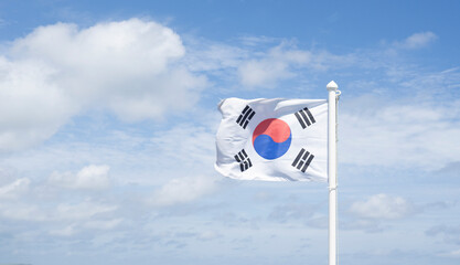 The Korean flag flutters in the clear sky.