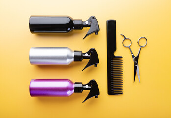 Set of hairdresser equipment: spray bottles, thinning scissors and hair comb. Top view of professional hairstyle tools isolated on yellow background