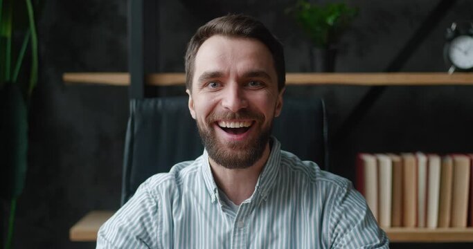 Happy bearded business man showing yeah gesture of victory, he achieved result, goals at modern office background