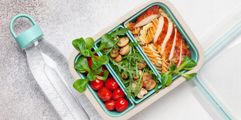Grilled chicken breast, pasta fusilli, arugula, mushrooms and fresh lamb salad in lunch box. Top view