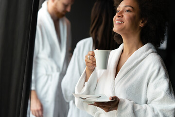 Beautiful black woman relaxing at luxury hotel spa wearing bathrobe and drinking coffee