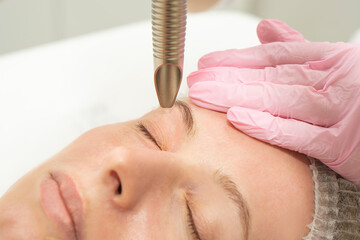close-up Doctor cosmetologist makes the procedure of laser dermal rejuvenation of the eyelids of...
