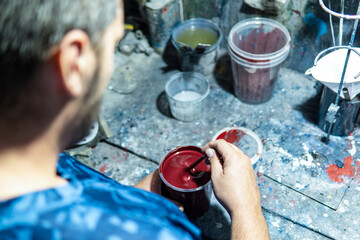 Fototapeta na wymiar Auto mechanic preparing red car paint in a workshop.