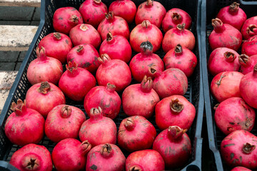 Ripe pomegranate fruits in open plastic boxes. Healthy eating. Selling fruit in the market. Pomegranate fruits are eaten raw, in cooked dishes, in drinks to make pomegranate juice.