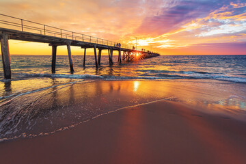 Port Noarlunga beach pier with people walking along at sunset, South Australia
