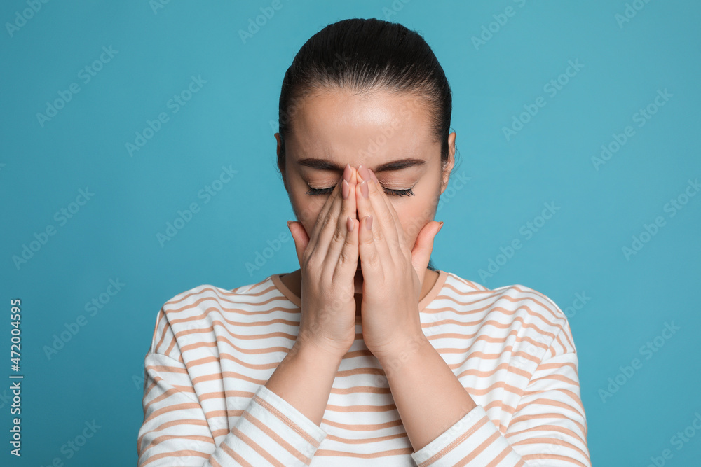 Canvas Prints Young woman suffering from headache on light blue background