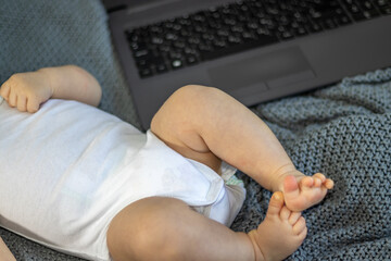 baby little boy toddler infant newborn in woman arms.female hands on black keyboard on a laptop.working in maternity leave. different finance sources.money, work from home.baby head on mom's shoulder