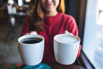 Closeup image of a young woman holding and serving two cups of coffee