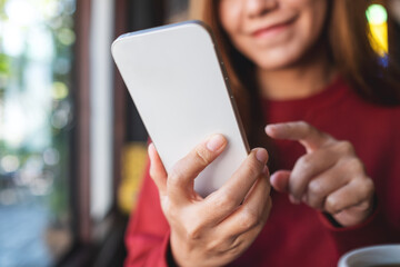 Closeup of a young woman holding and using mobile phone